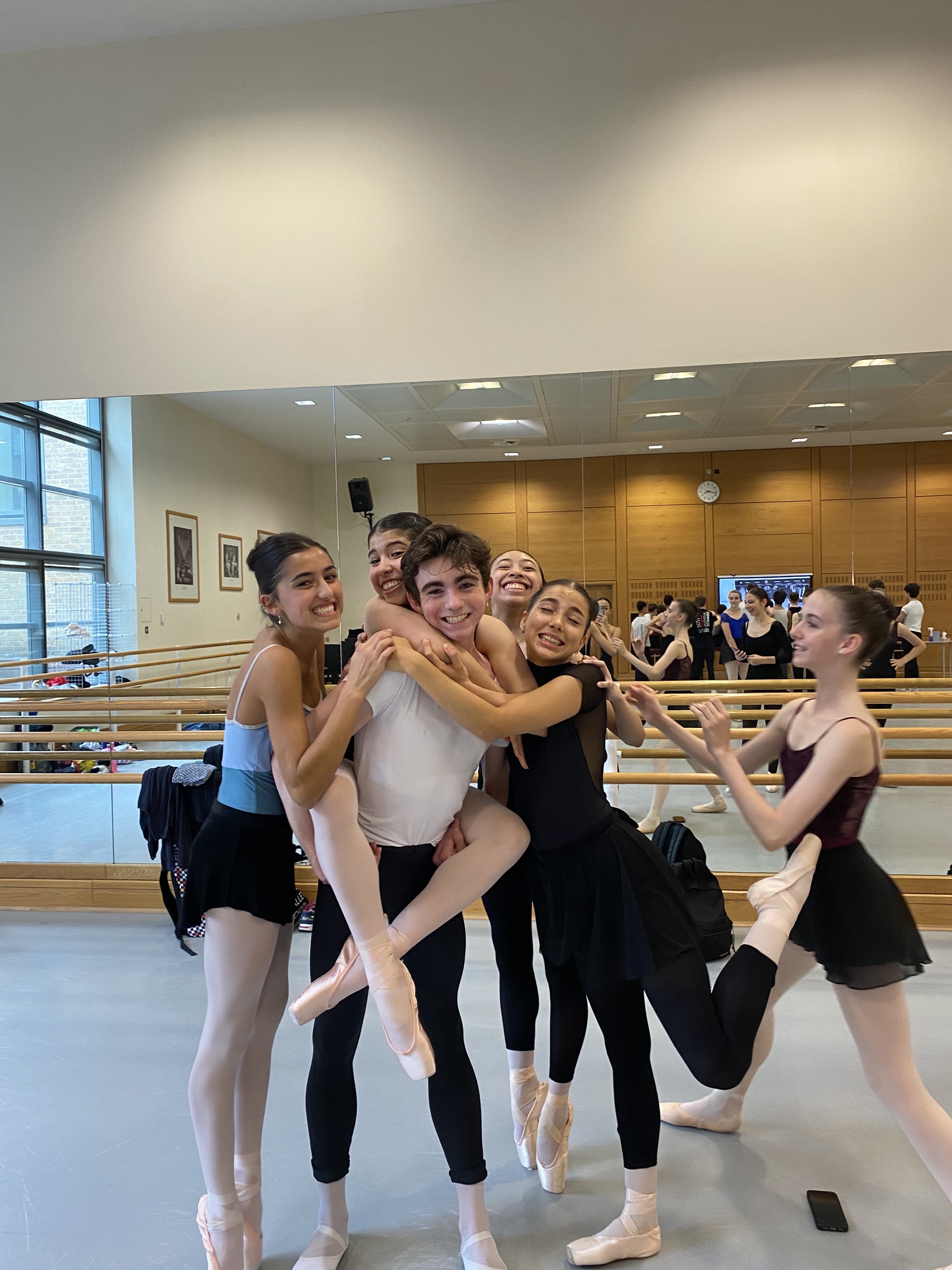 Female ballet students and male ballet students laughing in their studio at their full-time ballet training program