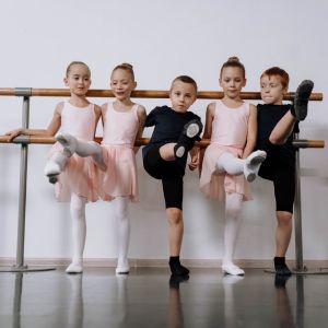 Image of five children in ballet clothing with the back to a ballet barre